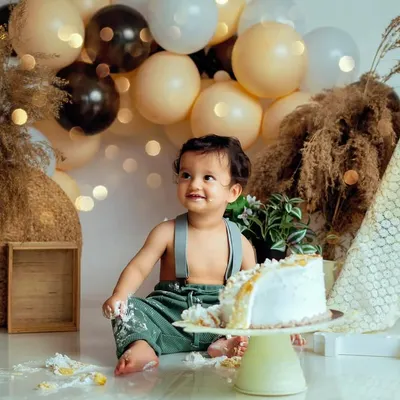 A bohemian-themed cake smash with earthy tones, pampas grass, and soft lights. This little one is just getting started on his delicious cake.
