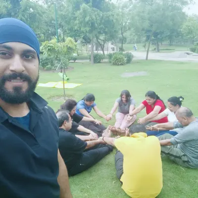 A selfie with my group during an outdoor yoga session. We are practicing a seated forward bend together, enjoying the fresh air and green surroundings.
