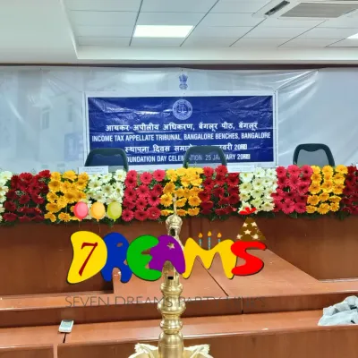 This is a formal stage decoration I did for a foundation day celebration at the Income Tax Appellate Tribunal office. The setup includes a long floral arrangement across the main table and simple corner bouquets for a professional look.