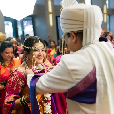 A key moment in a Maharashtrian wedding, the Varmala exchange. The bride's smile says it all as friends and family cheer them on.