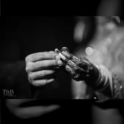 A powerful black and white shot of the ring exchange. This close-up focuses on the hands and the ring, symbolizing the promise and commitment at the heart of the ceremony.
