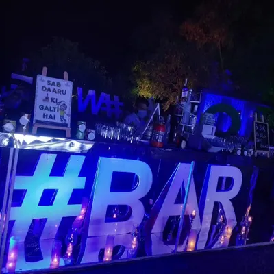 This modern bar setup is one of my most popular for evening parties. The large, blue-lit '#BAR' sign creates a striking focal point, while the humorous chalkboard sign adds a personal, lighthearted touch.
