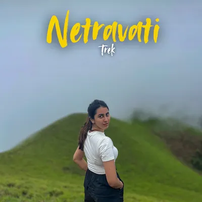 A trekker posing at Netravathi Peak, with the name of the trek overlaid. This is the picture perfect moment you'll want to capture.