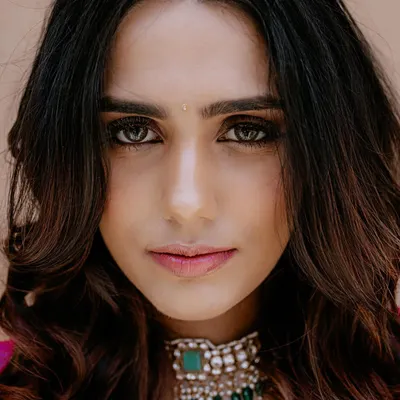 A stunning close-up bridal portrait. The direct gaze, flawless makeup, and intricate choker necklace are the focus of this beautiful shot.