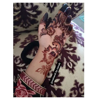 A perfect example of a clean and elegant Arabian henna design. The pattern flows diagonally across the back of the hand, emphasizing bold floral elements and leaving skin exposed for a modern effect.
