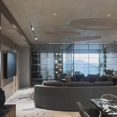 The open-plan living area in this modern apartment is defined by its curved sofa and dramatic marble flooring. We designed the space to feel both expansive and intimate, with recessed ceiling details and track lighting to highlight specific zones.