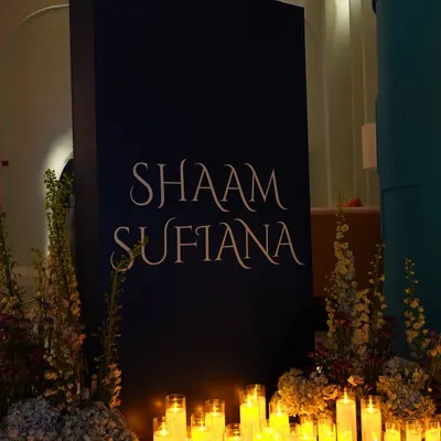 Setting the tone for a 'Shaam Sufiana'. A simple, elegant entrance sign surrounded by a sea of candles welcomes guests into an evening dedicated to soulful music and mystical ambiance.
