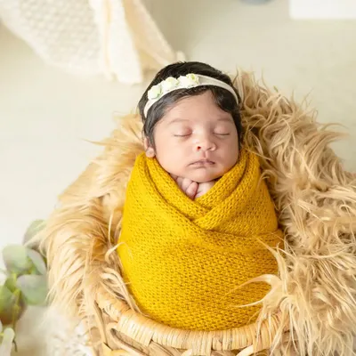 A peaceful newborn wrapped snugly in a yellow knit blanket, dreaming sweetly. I use soft textures and warm colors to create cozy and artistic newborn portraits.