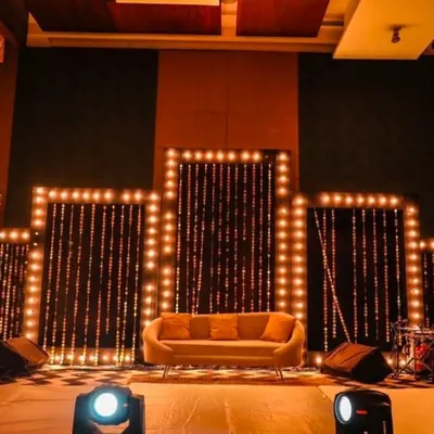 This stage design uses a series of panels framed with warm marquee bulbs and string light curtains to create a visually stunning backdrop. It's a versatile setup, ideal for a panel discussion, musical performance, or as a main stage for a company celebration.