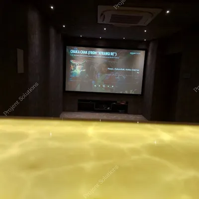 A view from the back of the room, emphasizing the scale of the fixed projector screen. Our installations ensure a bright, sharp 4K image that fills your field of view for a truly immersive experience.