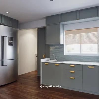 This view highlights the kitchen's practical layout, with the sink conveniently placed under a window. The consistent use of grey cabinetry and gold hardware creates a seamless and sophisticated look.