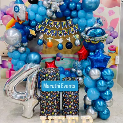 An out-of-this-world space theme for Veer's 4th birthday. This setup includes a balloon arch with astronaut and rocket ship foil balloons, themed plinths, and a large silver number '4'.