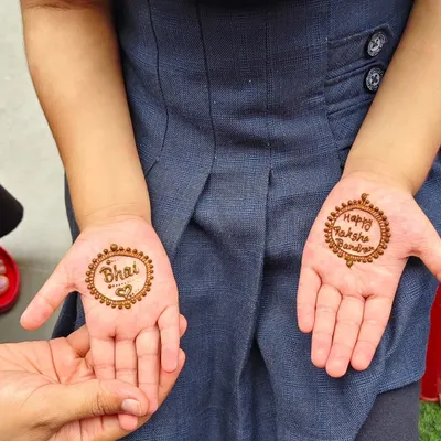 A simple and sweet Rakhi design for a little girl. One palm says 'Bhai' with a heart, and the other says 'Happy Raksha Bandhan'.