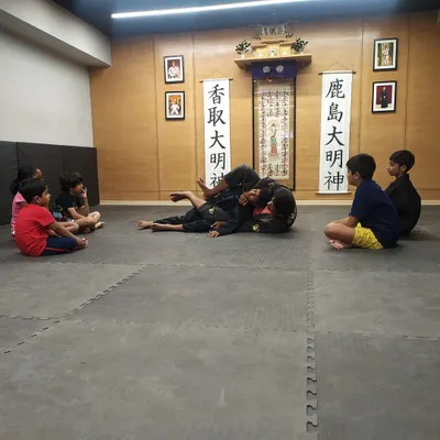 Our kids' jiu-jitsu classes are in full swing. Here, young students watch attentively as our instructor demonstrates a ground position, learning the importance of control and technique from an early age.