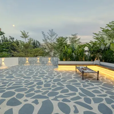 The spacious seating area of the Santorini-style terrace at dusk. The custom flagstone flooring, built-in bench with strip lighting, and surrounding greenery create a perfect ambiance for evening relaxation.