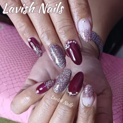 A dramatic set of almond nails combining deep burgundy, full-coverage holographic glitter, and a glitter fade with rhinestone details.