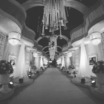 Create a spectacular first impression with a grand, fully decorated walkway. This design uses a series of arches, elegant white drapes, and floral urns to create a luxurious entrance experience.