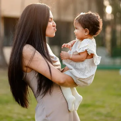 A sweet outdoor portrait of a mother making a kissy face at her baby. We focus on capturing these simple, loving gestures that beautifully illustrate the mother-daughter bond.