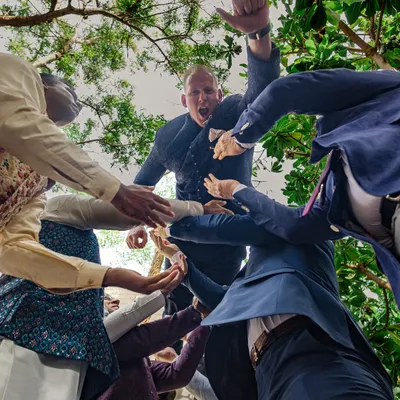 A unique, low-angle shot of the groom being lifted by his friends during the baraat. This captures the raw energy and excitement of the celebration from a dynamic perspective.