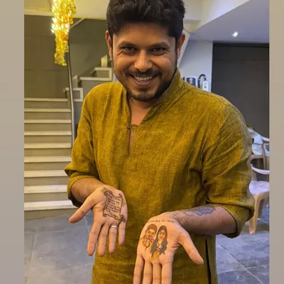 A groom proudly showing his unique mehandi. On one hand, a portrait of his beautiful bride, and on the other, a personal love letter written in henna for her to read.