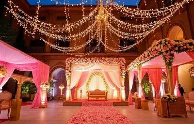 A classic royal wedding setup we created within the courtyard of a heritage palace. The decor features a soft pink color palette, a beautifully draped mandap, and a canopy of fairy lights, transforming the historic space into a fairytale wedding venue.