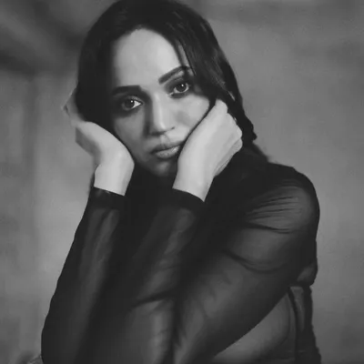 An intimate black and white portrait, where the model's direct gaze and hands framing her face create a powerful, emotional connection.