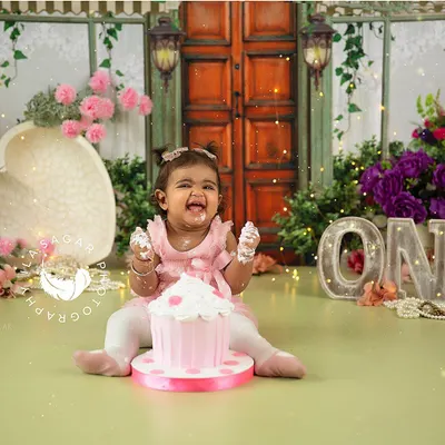 This is the moment of pure happiness I aim for in every cake smash session. Her joyful laugh and the colorful floral setup come together for a perfect first birthday memory.