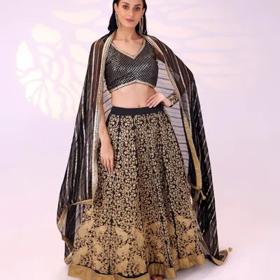 This black and gold lehenga is a timeless choice for a bridesmaid or wedding guest. The skirt features intricate gold embroidery, paired with a shimmering blouse and a striped dupatta that adds a modern touch.