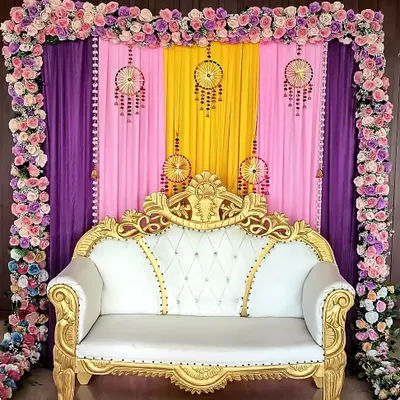 This beautiful seating arrangement is perfect for the mom-to-be at her baby shower. I used a backdrop of colorful drapes and a frame of artificial flowers to highlight the ornate white and gold sofa.