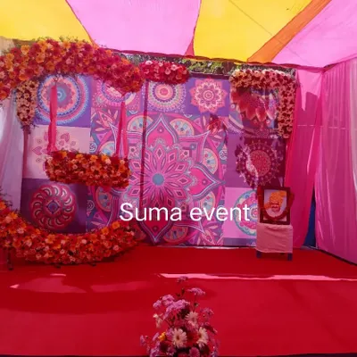This is a popular setup for Haldi and Mehendi events. It features a bright mandala print backdrop, a large floral swing for photos, and colorful pink and yellow drapes that create a festive atmosphere.