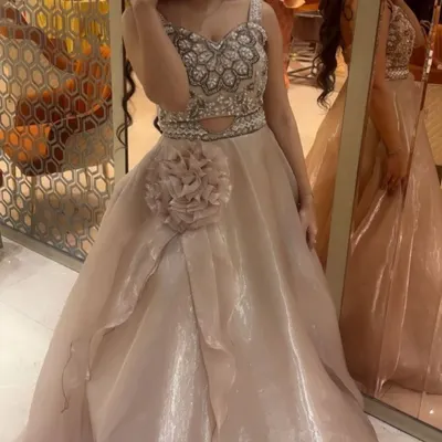This beige gown is one of my most popular pieces for engagement parties and receptions. It features a heavily embellished bodice with intricate beadwork and a flowing organza skirt with a floral detail.