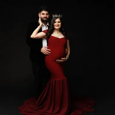 A regal maternity portrait for a queen awaiting her heir. The rich red gown and crown create a powerful, dramatic look against a classic dark backdrop.