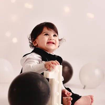 A simple and classic first birthday portrait. The glowing number '1' prop and a happy smile are all that's needed to mark this special milestone in a timeless way.