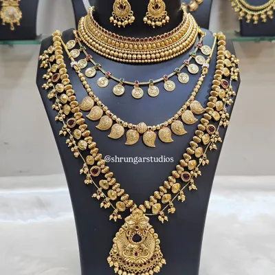 This is a classic multi-layered traditional gold-finish bridal set. It includes a choker, a coin necklace (putli haar), and two longer haars with matching earrings for a complete, royal look.