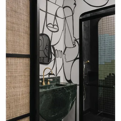 This shower bathroom continues the story of hand-painted murals from the adjoining media room. The black and white artwork leads into a dark, cave-like shower space, creating a corner filled with poetry and drama. The green marble sink adds a pop of rich color.