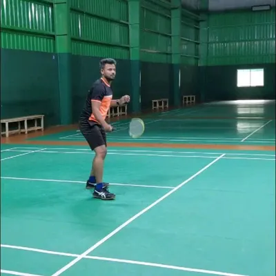 A player demonstrates the correct ready stance, a fundamental skill for any badminton player looking to improve their game on the court.