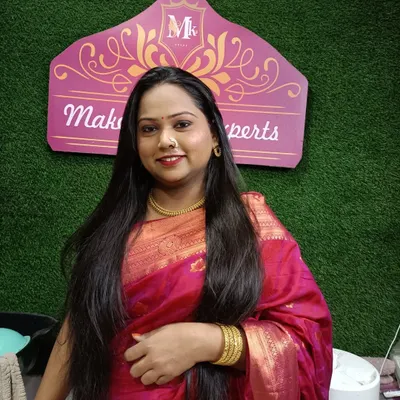 A photo of a happy client at my makeup studio. The green and pink background is a part of my dedicated space for makeovers.