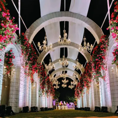 A truly grand welcome. This magnificent entrance features a long passageway of arches adorned with bougainvillea and illuminated by crystal chandeliers, leading to a palace-like facade.