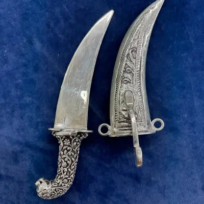 Our antique silver dagger shown alongside its intricately carved sheath. The detailed floral patterns on both the hilt and the scabbard make this a remarkable collectible or decorative piece.