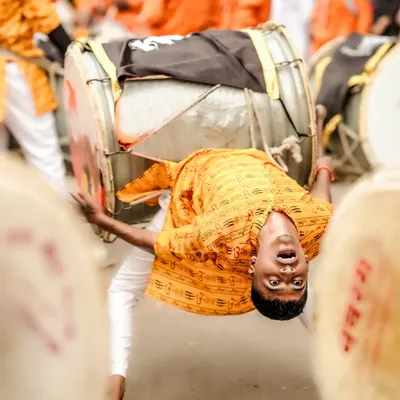 Capturing the peak of energy and devotion. This dynamic shot freezes a dhol player in a moment of acrobatic performance during a street festival.