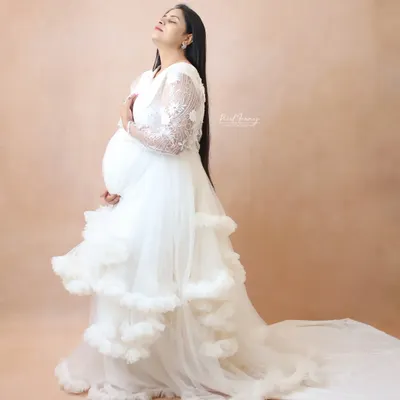 Feel serene and beautiful in this white ruffle maternity gown. It features delicate lace sleeves and a long train, all made with comfortable, skin-friendly fabric. Home delivery and trials are available across Mumbai.