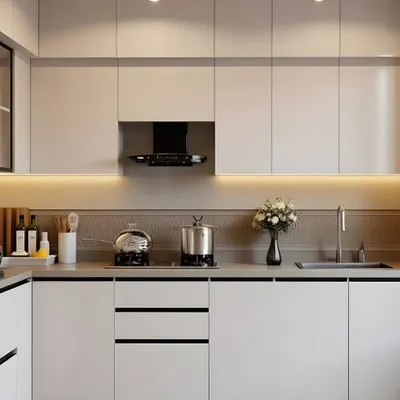 A minimalist parallel kitchen design featuring all-white handle-less cabinets. The warm under-cabinet lighting and textured backsplash add depth and character, proving that simple can be stunning.