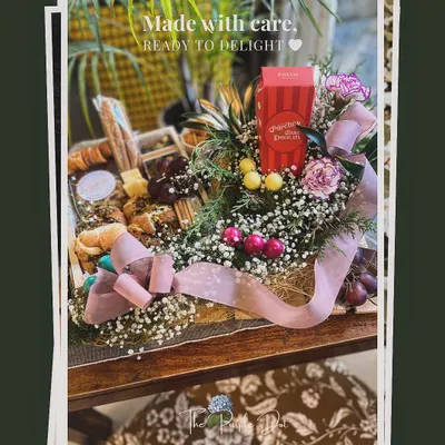 A birthday surprise charcuterie hamper, made with care and ready to delight. This gift combines savory breads, cheeses, and grapes with sweet treats and a beautiful floral arrangement.