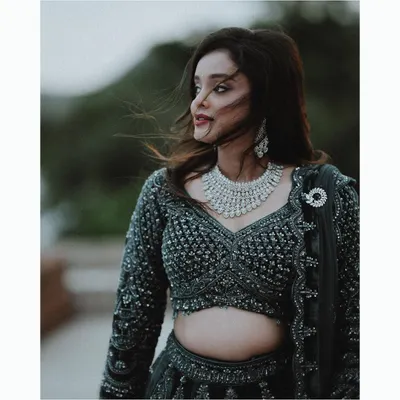 A stunning portrait of the bride with her hair blowing in the wind, showcasing her beautiful diamond necklace and elegant evening lehenga.