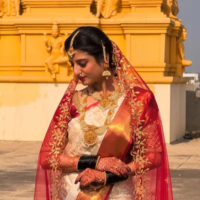 A demure and elegant bridal portrait. The sheer veil and traditional jewelry are perfectly complemented by makeup that highlights the bride's natural beauty for her wedding day.