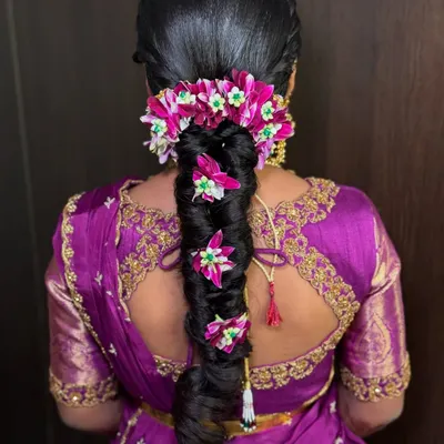 A close-up of the stunning floral braid created for Saanvi's half saree ceremony. The vibrant pink flowers are woven into the braid, creating a beautiful and traditional look.