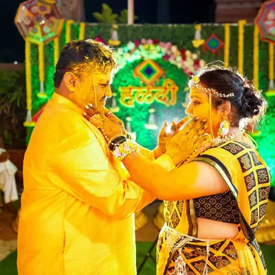 A candid moment during the Haldi ceremony, where the bride and groom lovingly apply turmeric paste to each other against a festive backdrop.
