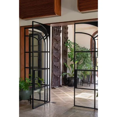 The arched, black-framed glass doors that we designed for the Alibaug house. They pivot to open up the space completely, blurring the line between the entrance foyer and the inner living areas.
