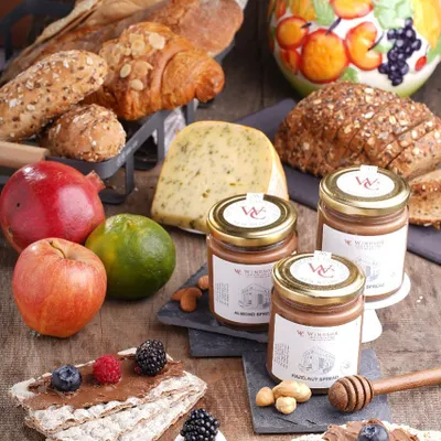 Our almond and hazelnut spreads featured in a wholesome breakfast setting. Surrounded by fresh fruits, breads, and cheese, this image shows the versatility of our spreads as part of a gourmet meal.