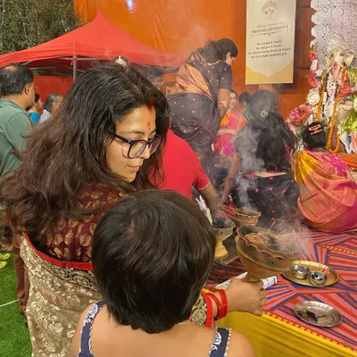 A woman participates in the Dhunuchi Naach, the fragrant smoke from the earthen pot creating a mystical atmosphere. This is a key ritual of Durga Puja celebrations.